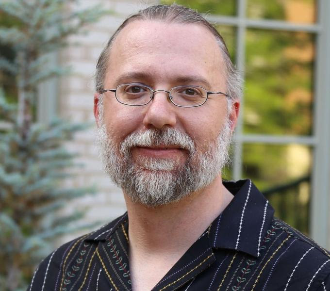 Greg Siering poses for a headshot. He wears a blazer and tie.