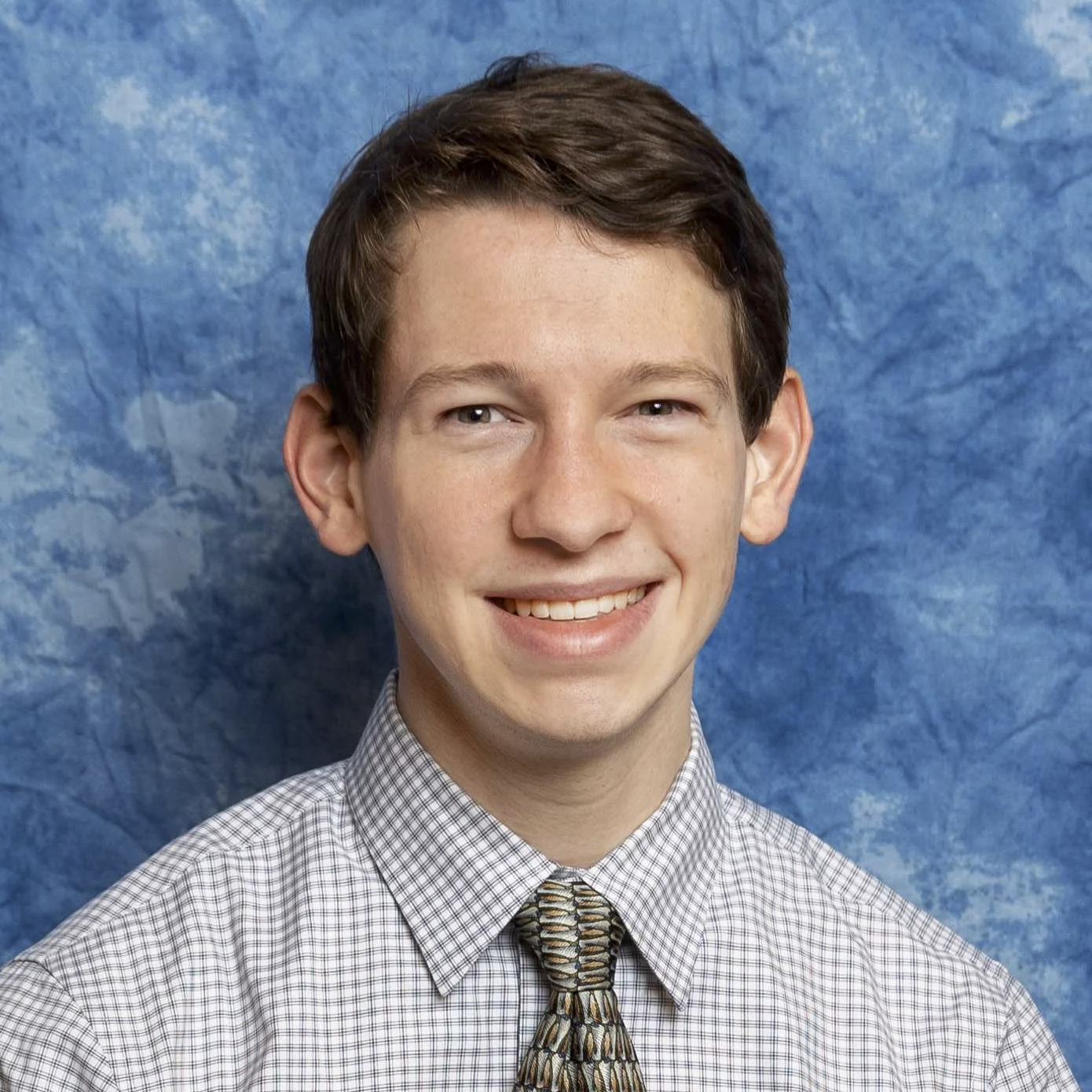 Greg Siering poses for a headshot. He wears a blazer and tie.